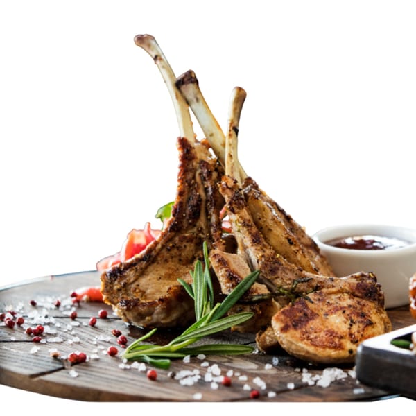 Grilled lamb chops with rosemary, red peppercorns, and sea salt on a wooden board.
