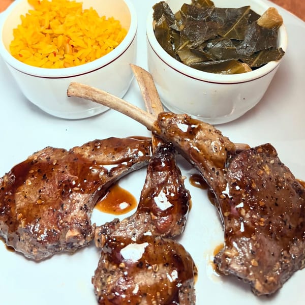 Four glazed lamb chops with yellow rice and collard greens in white bowls on a plate.